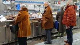 Varias personas compran pescado y marisco en la plaza de Lugo de A Coruña.