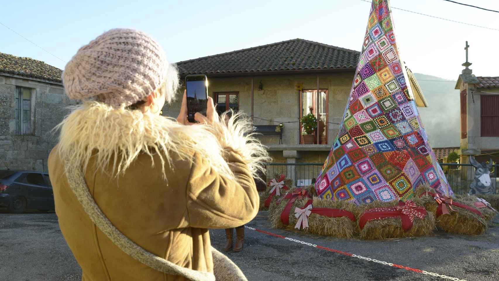 Una persona toma una fotografía frente al árbol de Navidad de Ousende hecho con ganchillo, a 18 de diciembre de 2023.