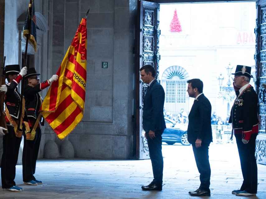 Pedro Sánchez y Pere Aragonès se inclinan ante la señera, antes de su reunión en el Palau de la Generalitat.
