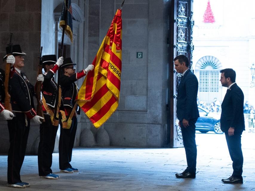 Pedro Sánchez y Pere Aragonès se inclinan ante la señera, antes de su reunión en el Palau de la Generalitat.