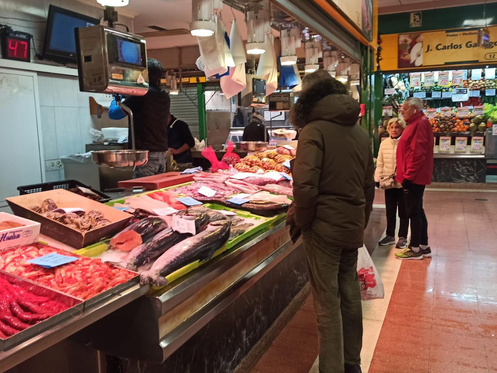 Un hombre observa los precios del marisco y del pescado en un puesto del mercado del Campillo en Valladolid