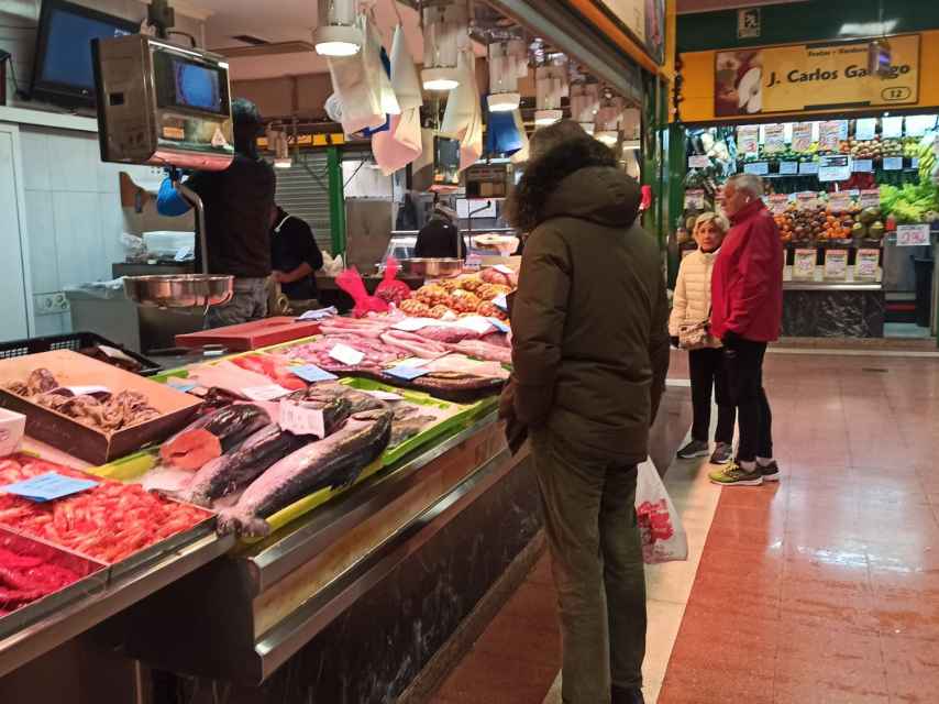 Un hombre observa los precios del marisco y del pescado en un puesto del mercado del Campillo en Valladolid