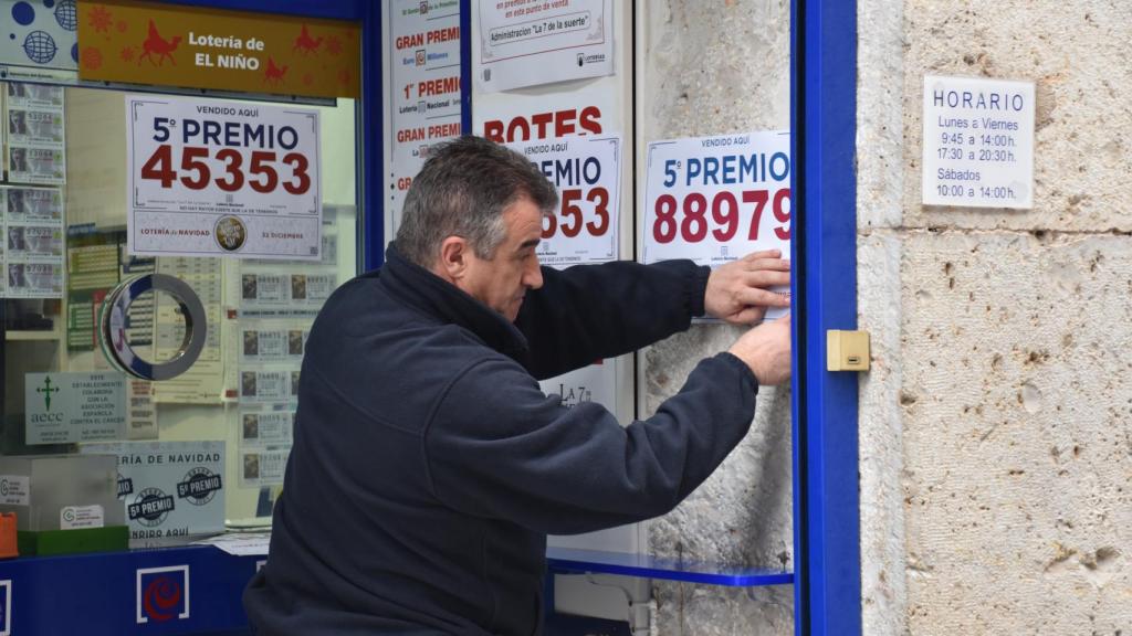 Un trabajador colocando el cartel del quinto premio de la Lotería Nacional