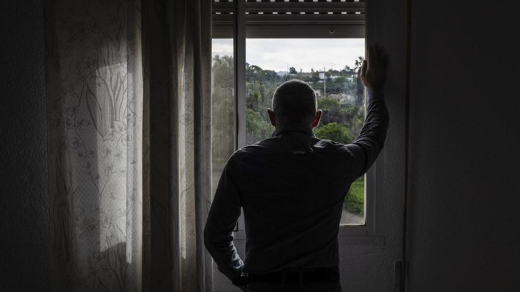 Imagen de archivo de un hombre adulto mirando por la ventana.