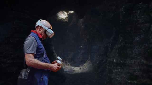 Un fotomontaje con un hombre usando un equipo de realidad virtual en una de las cuevas recreadas por Murciélagos Málaga.