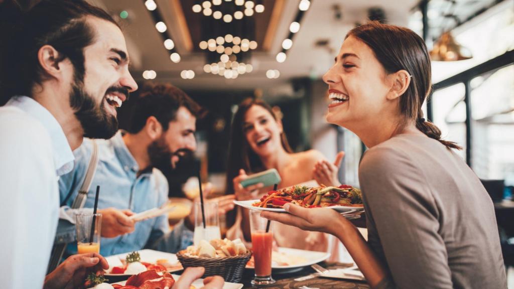 Imagen de una mujer en primer plano comiendo con amigos