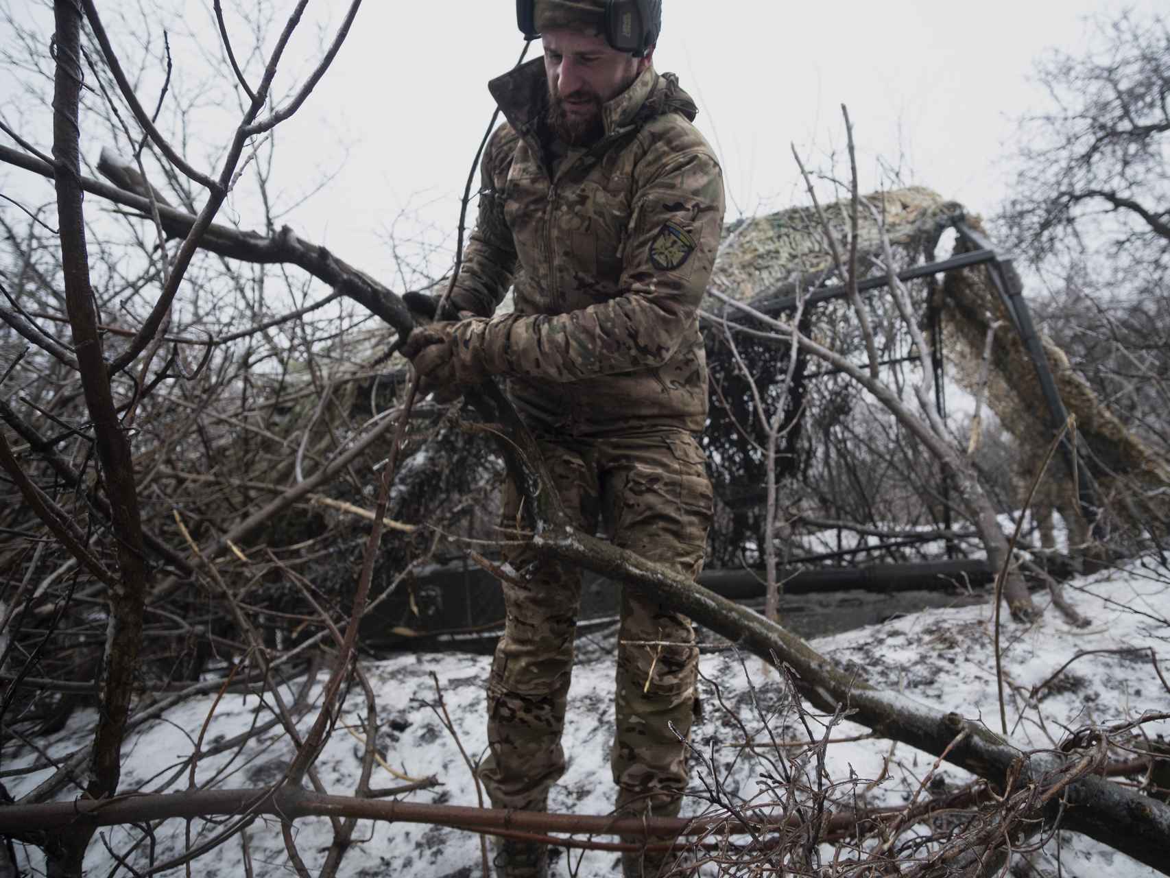 Tras lanzar un ataque de artillería contra las líneas rusas, un sodado ucraniano de la Brigada 17 cubre con ramas el cañón 2S1 que operan para que no lo detecten los drones enemigos.