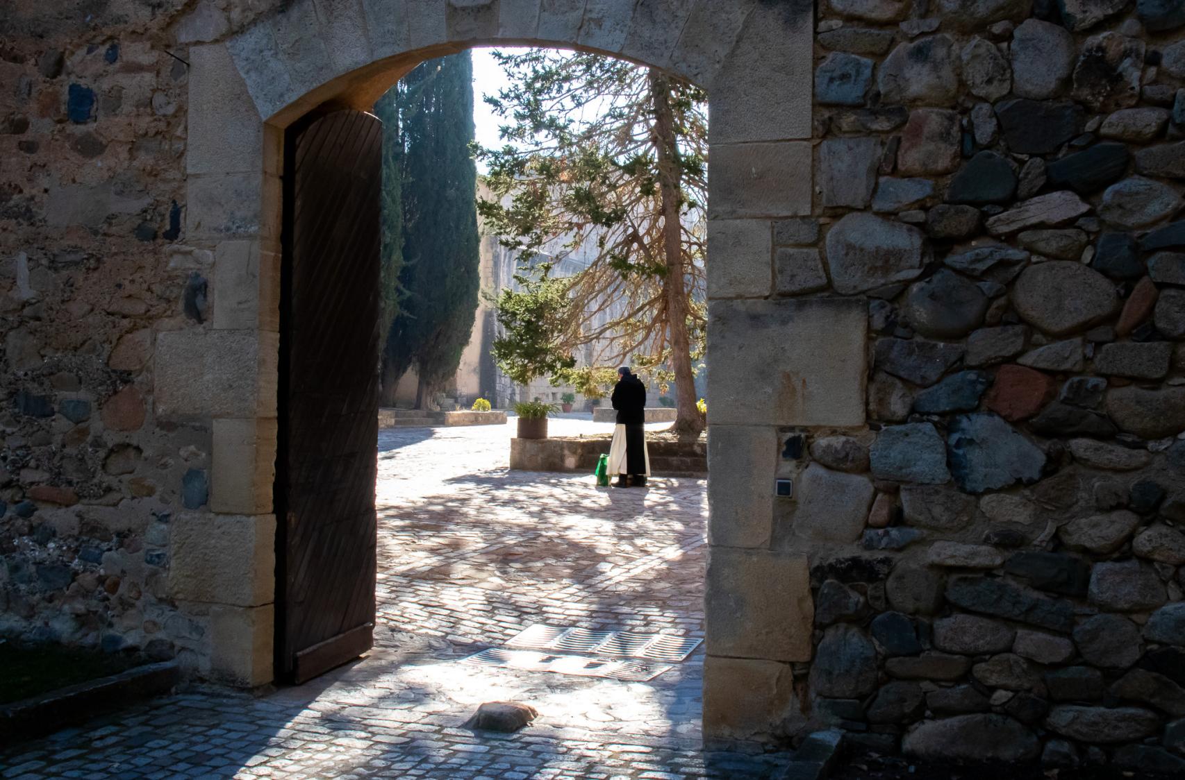 El prior cisterciense, fray Rafael, porta unas bolsas mientras cruza el patio interior de la zona de clausura del monasterio de Poblet.