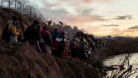 Un grupo de migrantes bordea del río Bravo para cruzar de Piedras Negras (México) a Eagle Pass (Texas).