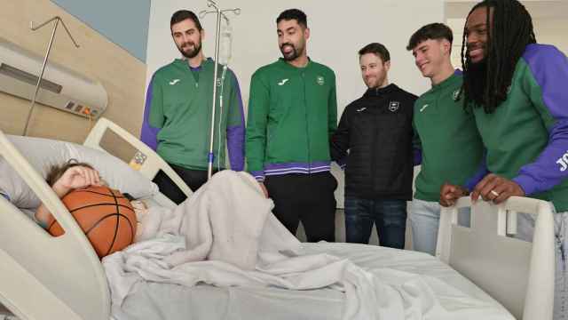 Los jugadores del Unicaja Baloncesto visitan a uno de los niños ingresados y le dan un balón.