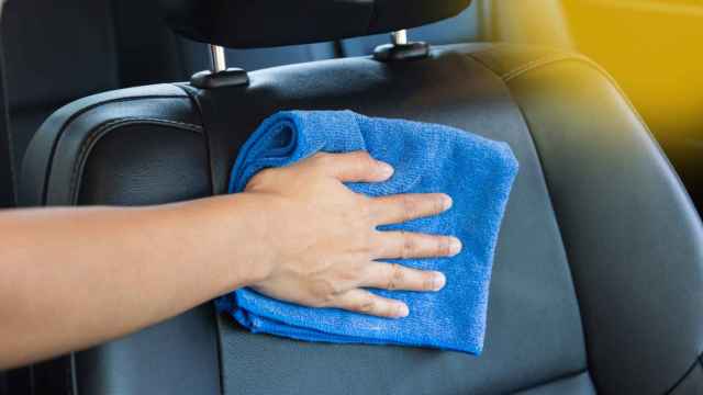 Imagen de una mano con un paño limpiando el interior de un automóvil