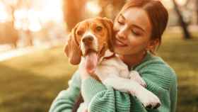 Imagen de una mujer abrazando a un perro beagle en el parque