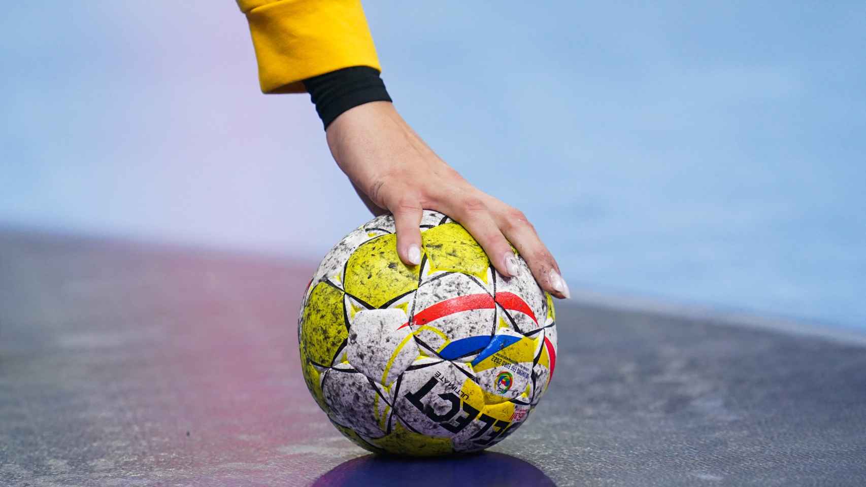 Una jugadora coge el balón del suelo durante un partido.