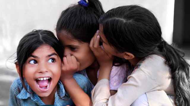 Imagen de archivo de unas niñas alegres susurrando un secreto en el oído