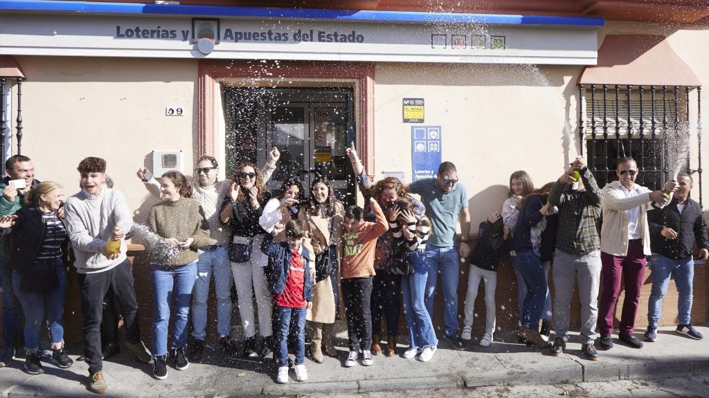 Varias personas celebran los décimos agraciados tras tocarles parte del tercer premio, 18918, de la Lotería del Niño 2023.