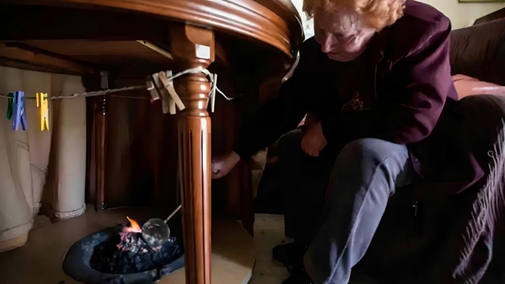 Una mujer prepara un brasero de picón en Sevilla.