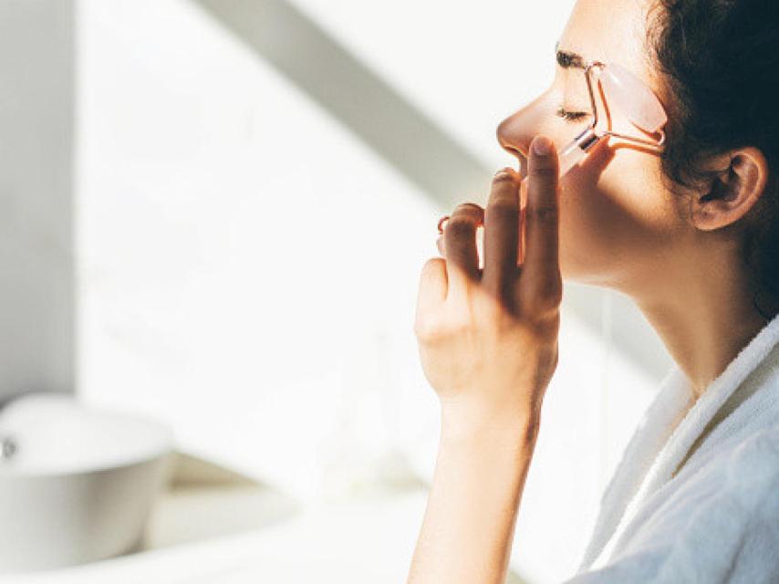 Una mujer haciéndose un masaje facial.