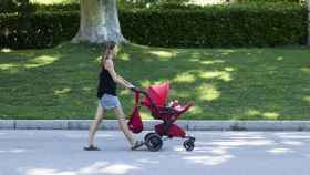 Una mujer pasea con un carrito de bebé.