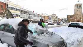 Una pareja retira la nieve de su vehículo en la localidad palentina de Aguilar de Campo