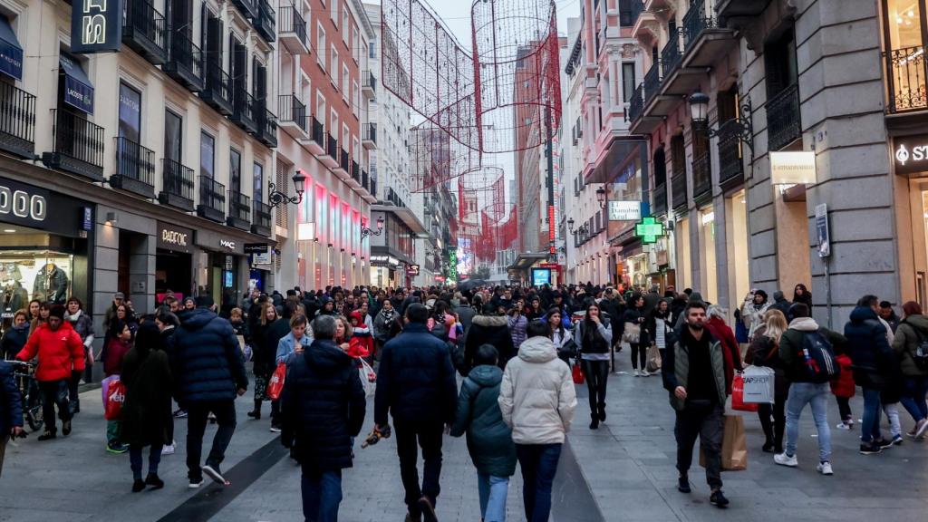 Cientos de personas, con compras, en la calle comercial de Preciados, Madrid