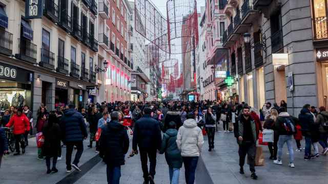 Cientos de personas, con compras, en la calle comercial de Preciados, Madrid