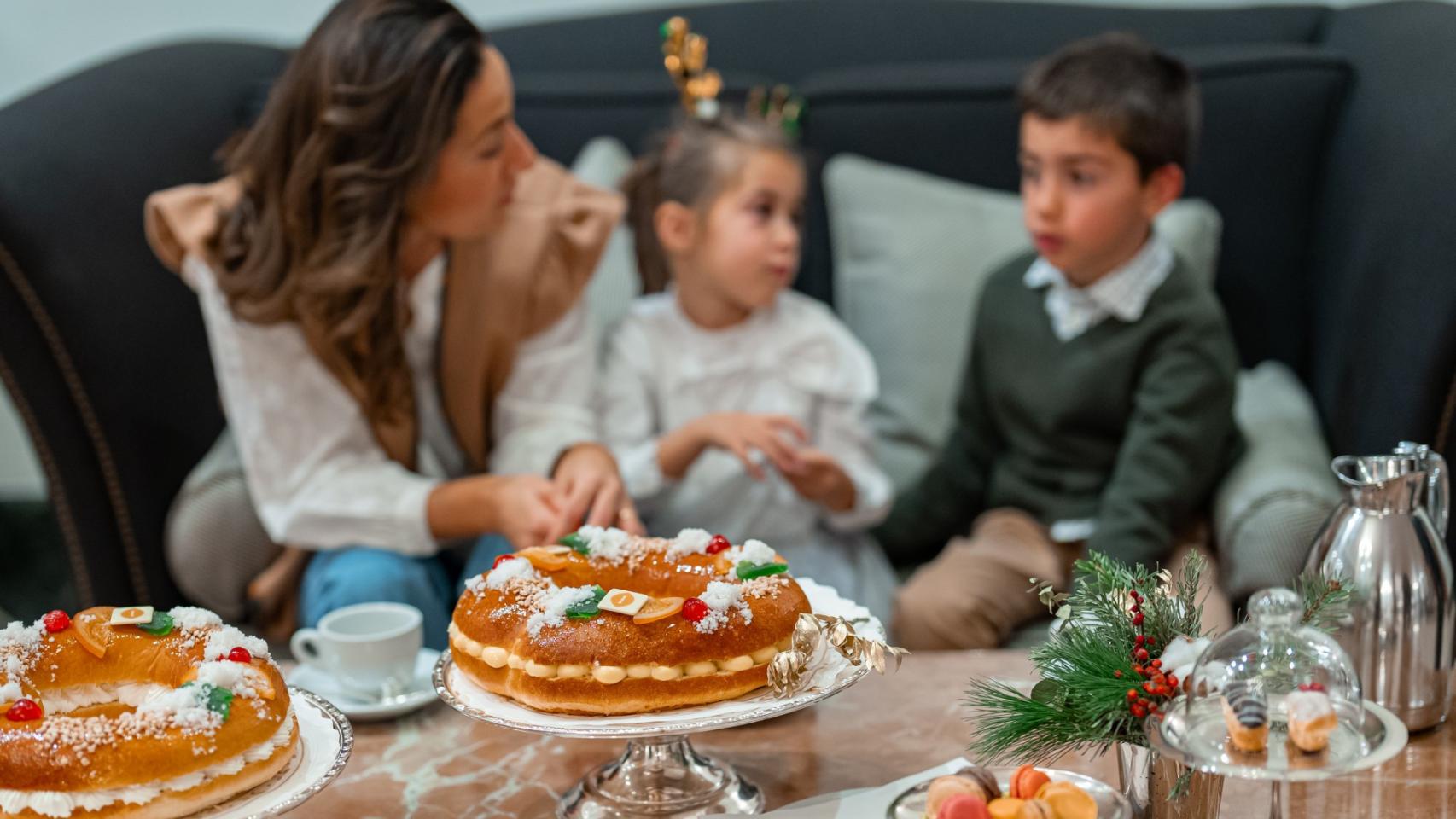 Unos niños esperan la llegada de los Reyes Magos mientras disfrutan de un roscón de Reyes.