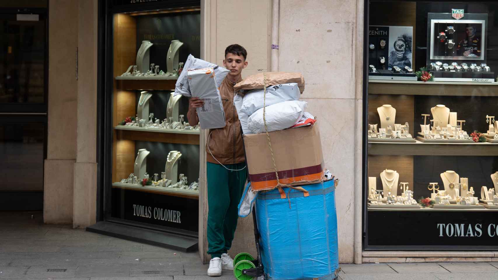Un joven se apoya junto a cajas con compras durante la campaña de Navidad