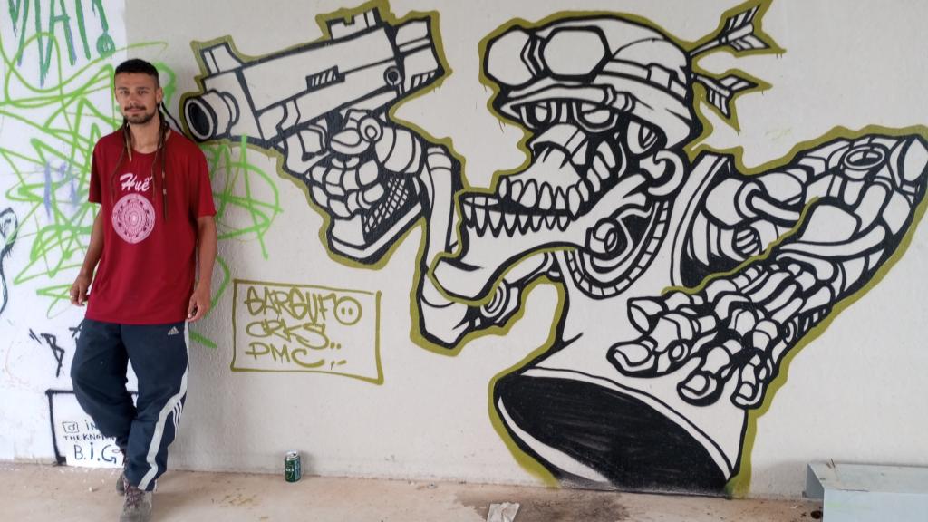 Jesús posa junto a uno de los grafitis que han hecho los asistentes a la rave que ha ocupado el circuito del Moto Club Fuente Álamo.