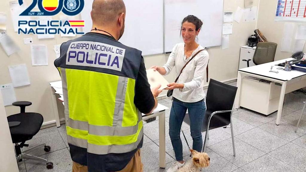 El agente de la Policía Nacional entrega el regalo hurtado a la propietaria para las Navidades.