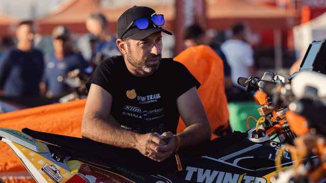 El piloto Carles Falcón junto a su moto en el Dakar