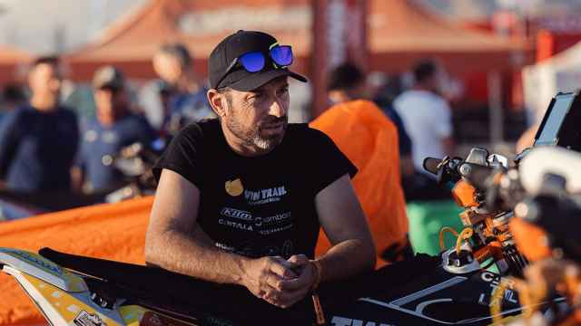 El piloto Carles Falcón junto a su moto en el Dakar