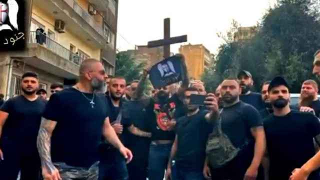 Un grupo de hombres con camisetas negras porta una cruz y un emblema de Junoud al-Rabb.