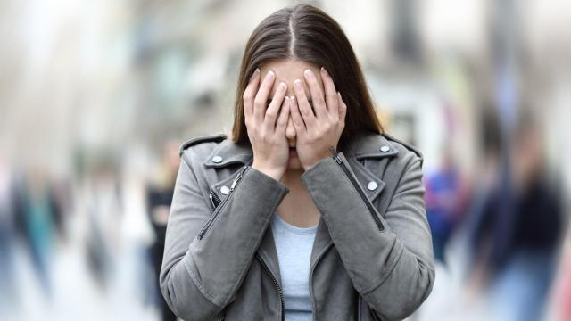 Imagen de una mujer cubriéndose la cara en medio de la calle