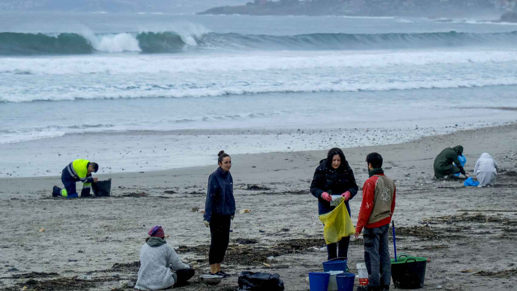 Varios voluntarios recogiendo los pellets de plástico en una playa gallega