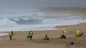 Operarios de empresas contratadas por la Xunta retiran los pellets o bolitas para fabricar plástico que aparecen en las playas gallegas y de Asturias.