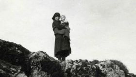 Una mujer observa desde lo alto los destrozos con su hijo en brazos en Ribadelago