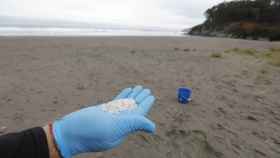 Un operario coge 'pellets' de plástico en la playa Otur, en Asturias.
