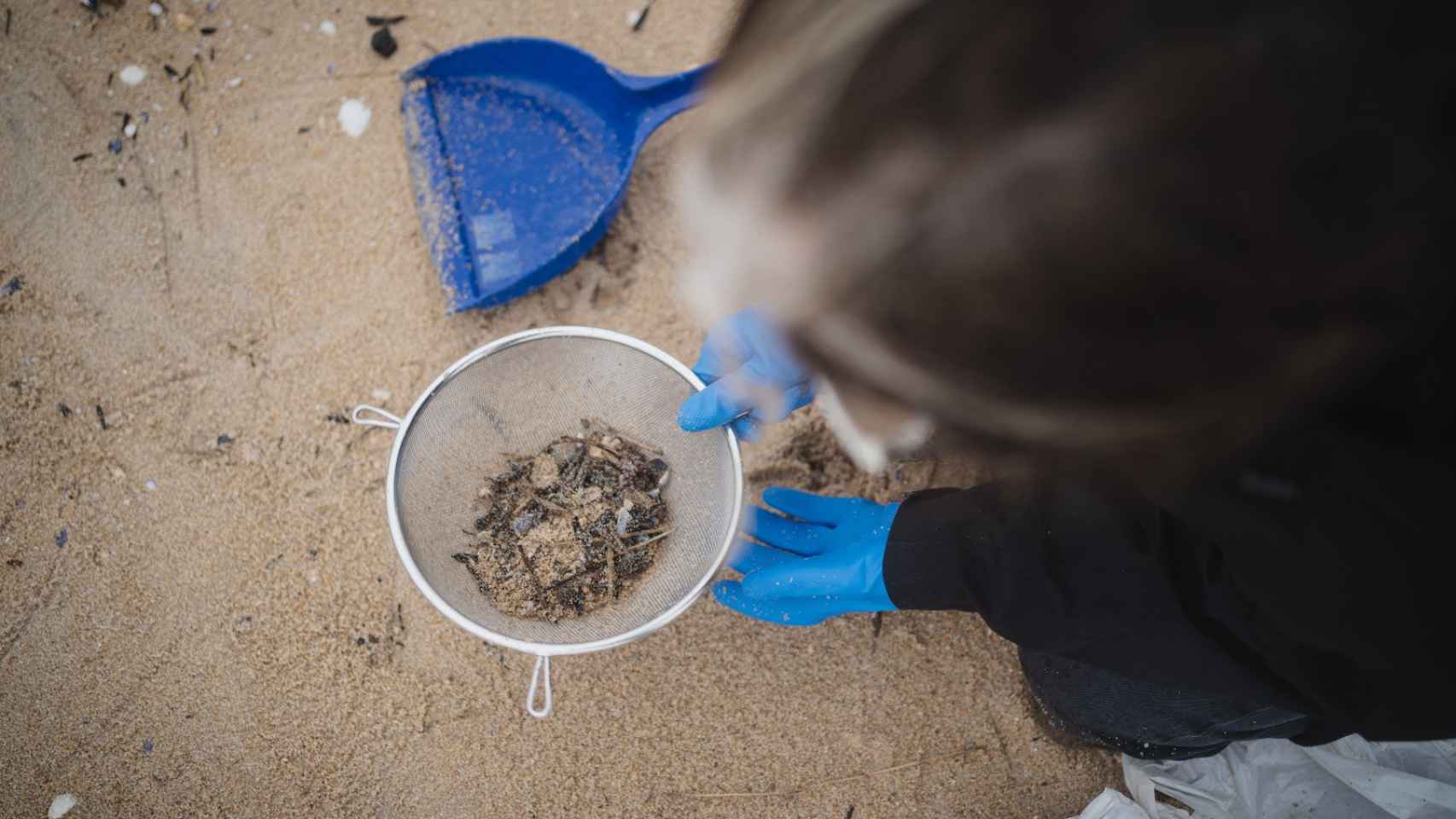 María Arceo cuela la arena para separarla de los plásticos