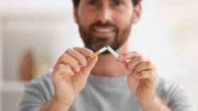 Un hombre rompe un cigarro como un intento de dejar de fumar.