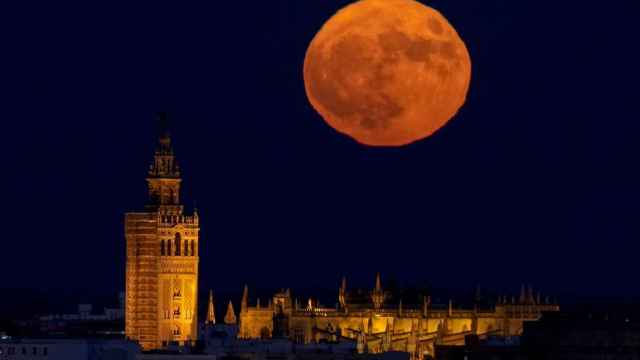 Imagen de una luna llena detrás de la Giralda y la catedral de Sevilla.
