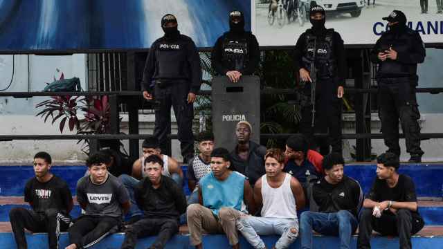Policías custodian a un grupo de detenidos en Guayaquil.