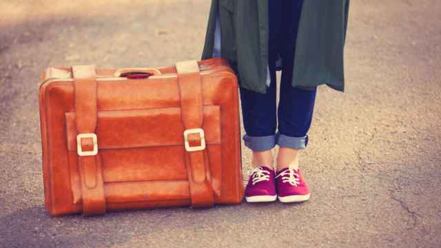 Una mujer con maleta dispuesta a viajar.