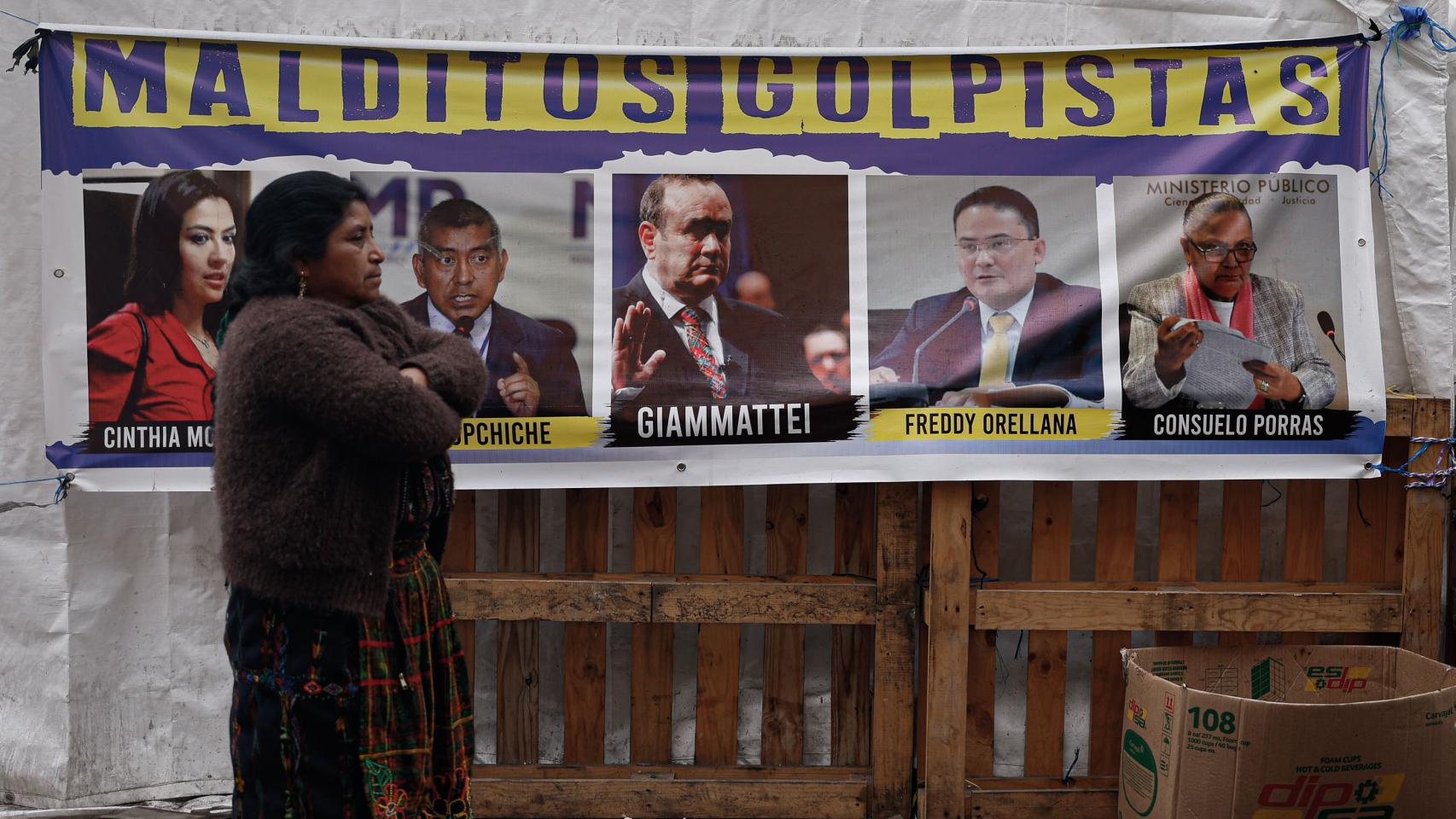 Una mujer camina frente a un cartel de protesta en la sede de la Fiscalía de Guatemala, este viernes.