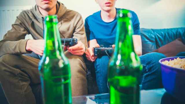 Imagen de archivo de dos jóvenes jugando a videojuegos y bebiendo cervezas.