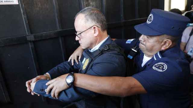 Un oficial registra al exministro de Gobernación Napoleón Barrientos después de su captura, el jueves en Guatemala.
