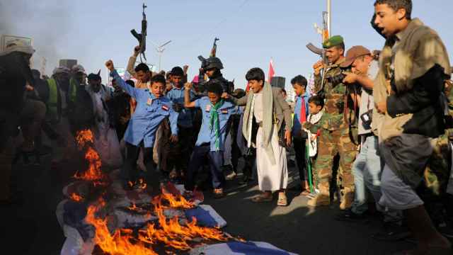 Un grupo de hombres yemeníes quema y pisotea banderas israelíes y estadounidenses, este viernes en Saná.