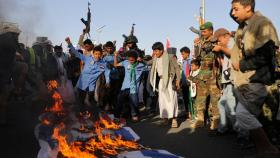 Un grupo de hombres yemeníes quema y pisotea banderas israelíes y estadounidenses, este viernes en Saná.