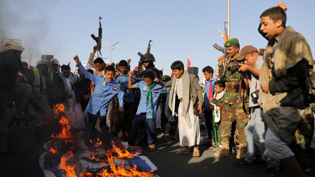 Un grupo de hombres yemeníes quema y pisotea banderas israelíes y estadounidenses, este viernes en Saná.