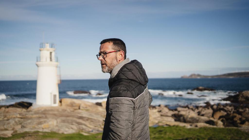 David Lema pasea entre las rocas, con el faro de fondo