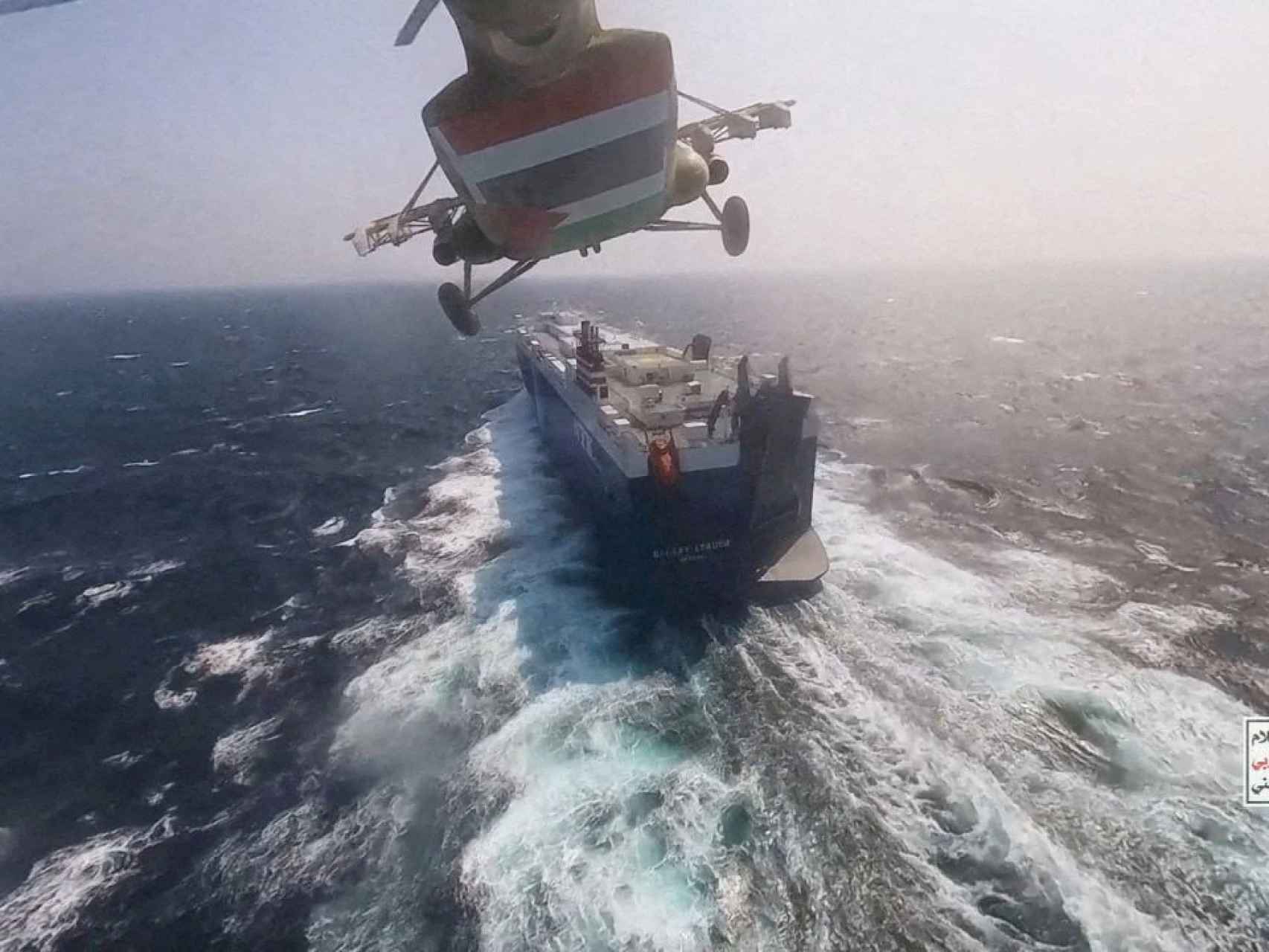Un helicóptero militar hutí vuela por encima de un barco mercante en el mar Rojo.